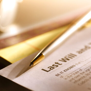 A Last Will And Testament sitting on a desk with a pen on top of it.