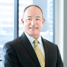 A professional headshot of Alan Shoer in front of windows.