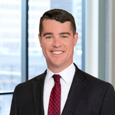 A professional headshot of Patrick Coyne in front of windows.