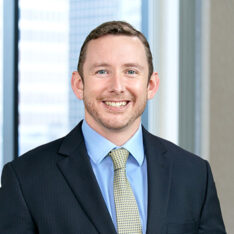 A professional headshot of Patrick Sampson in front of windows.