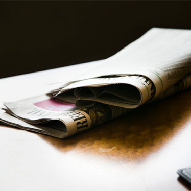 Stock photo of newspapers sitting on top of a wooden table.