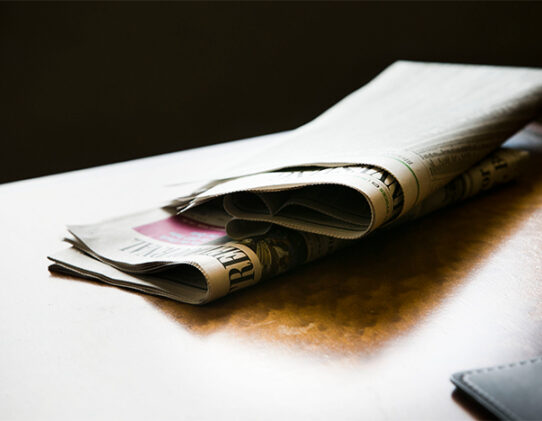 Stock photo of newspapers sitting on top of a wooden table.