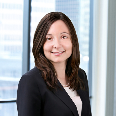 A professional headshot of Brenna Force in front of windows.