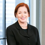 Professional headshot of Victoria Almeida with windows in the background.