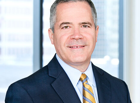 A professional headshot of Robert Brooks in front of windows.