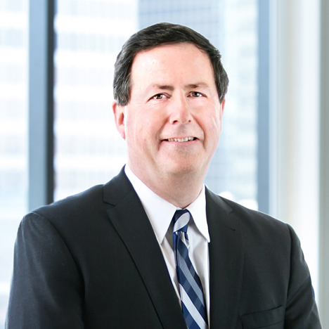 A professional headshot of Paul Campellone in front of windows.