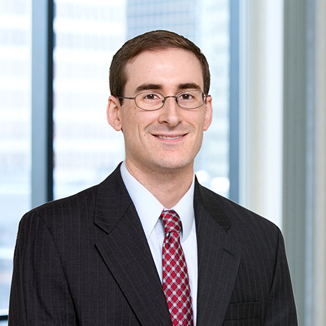 A professional headshot of Stephen Connelly in front of windows.