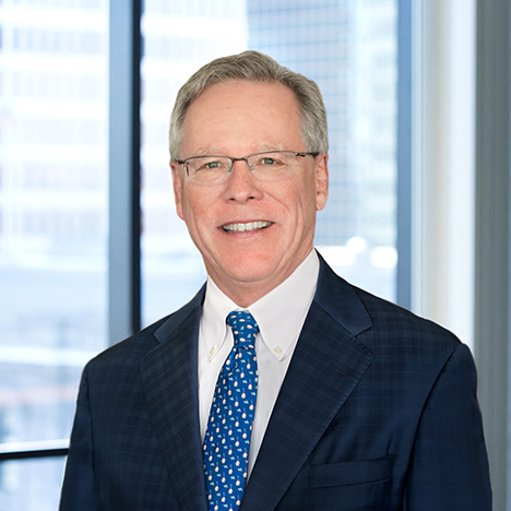 A professional headshot of William Dolan in front of windows.