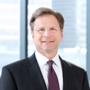 A professional headshot of Robert Stolzman in front of windows.