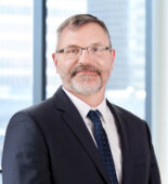 A professional headshot of Jeffrey Techentin in front of windows.