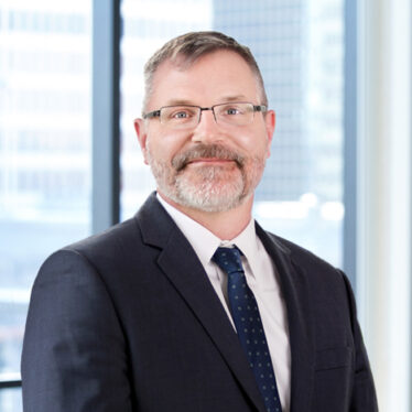 A professional headshot of Jeffrey Techentin in front of windows.