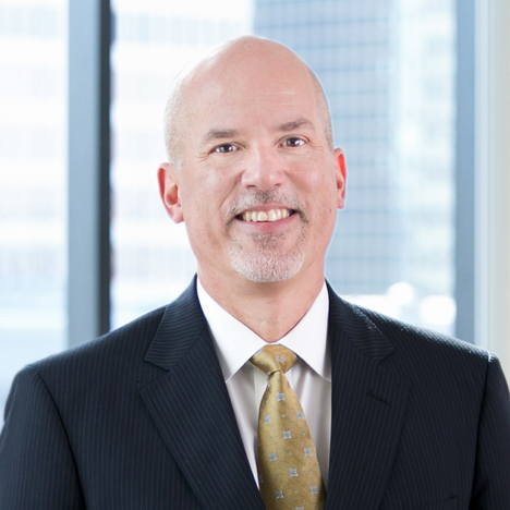 A professional headshot of R. Bart Totten in front of windows.