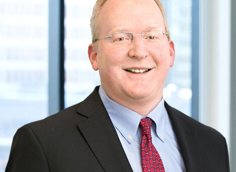 A professional headshot of Daniel Holmander in front of windows.