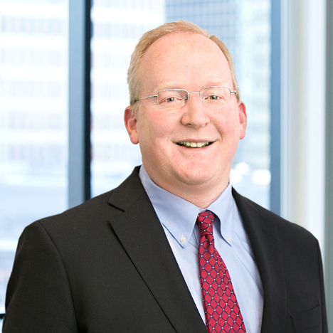 A professional headshot of Daniel Holmander in front of windows.