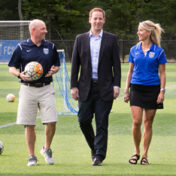 An attorney from Adler Pollock & Sheehan P.C. walking with two representatives of the FC Stars on their new state-of-the-art field.