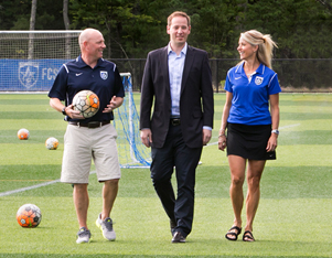 An attorney from Adler Pollock & Sheehan P.C. walking with two representatives of the FC Stars on their new state-of-the-art field.