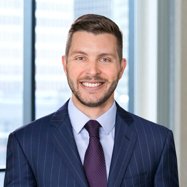 A professional headshot of Daniel Procaccini in front of windows.