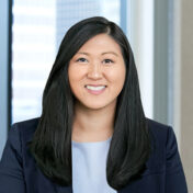 A professional headshot of Kim Dooley in front of windows.