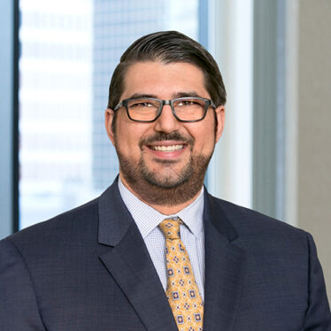 A profesional headshot of Christopher Yagoobian in front of windows.