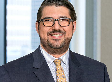 A profesional headshot of Christopher Yagoobian in front of windows.